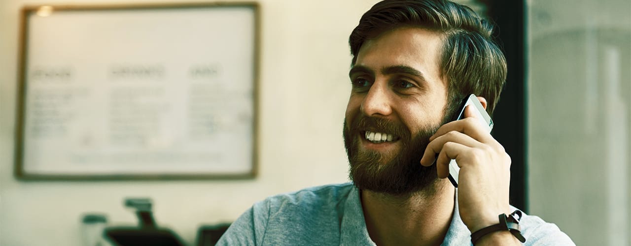 Photo of a man smiling while talking on a mobile phone